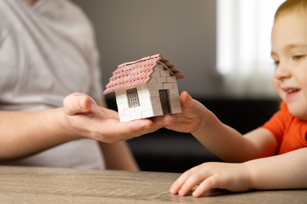 photo of man handing a model house to a child to illustrate inherited and gifted taxes