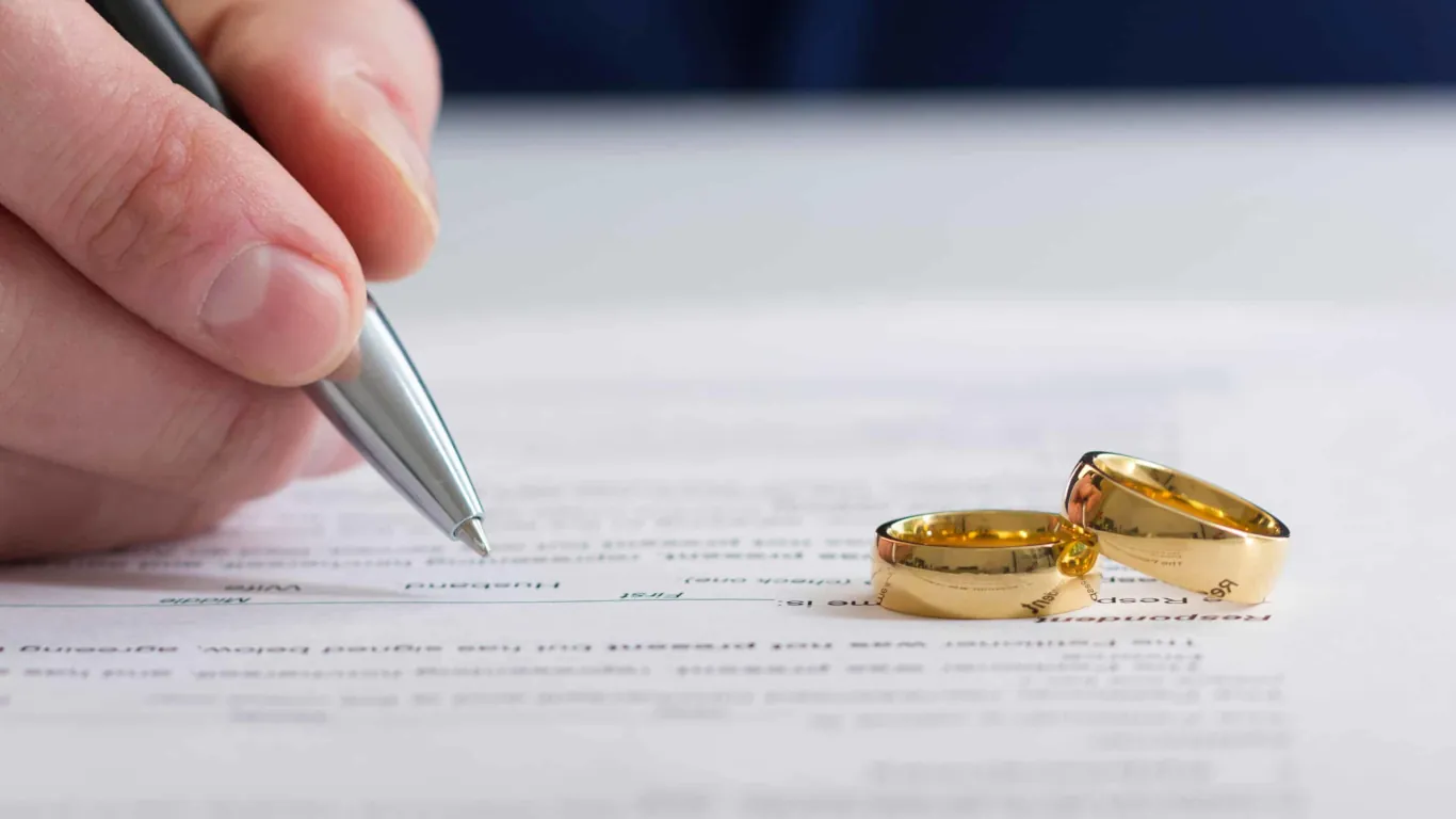 Signing divorce agreement with wedding rings