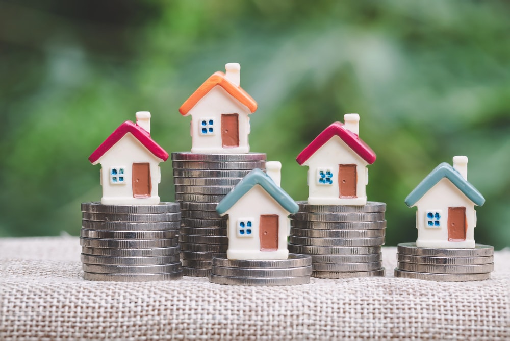 miniature homes on stacks of coins to demonstrate property tax burden