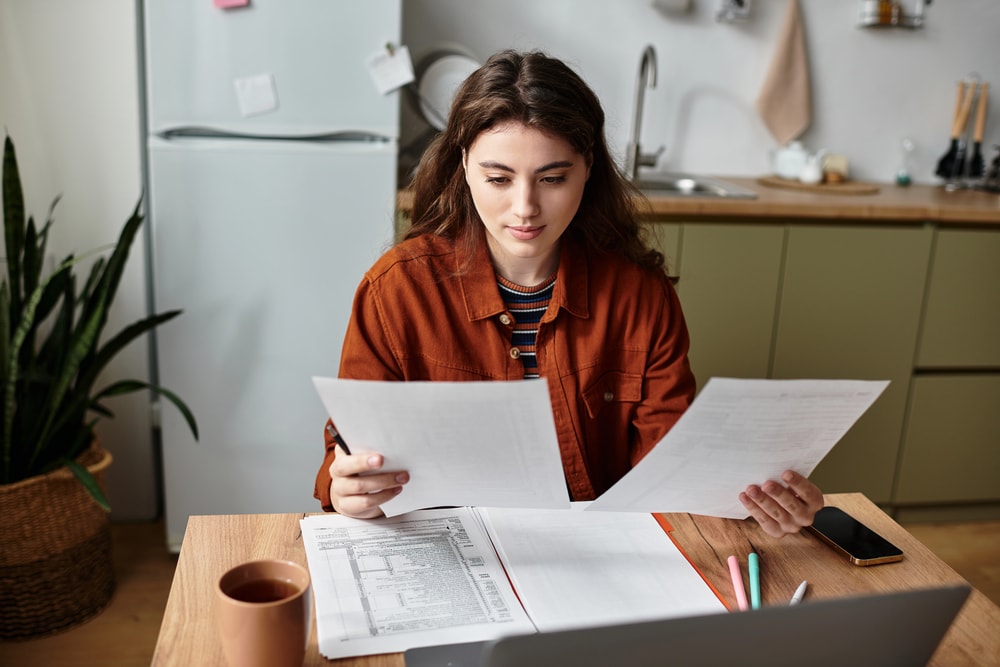 a woman sitting in her kitchen, reading her tax documents and property tax laws