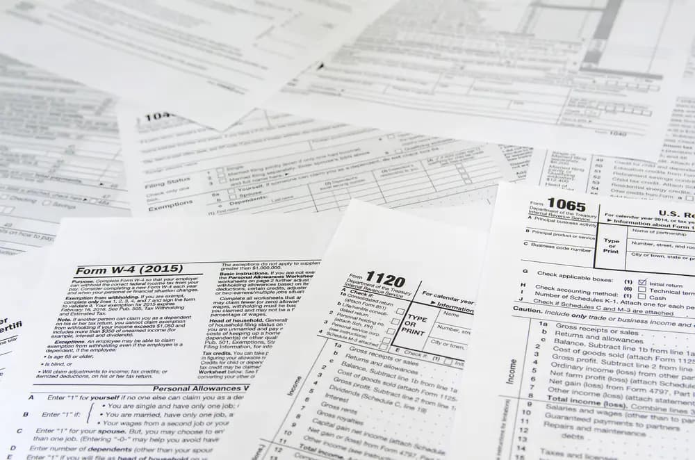 Federal tax forms W-4, 1120 and 1065 on a table