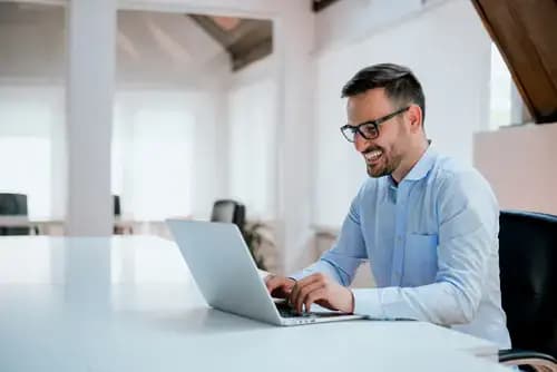 Image of a man smiling while working on his laptop.